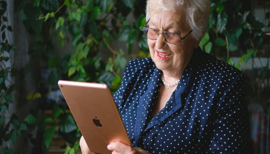 Happy elderly woman looking at an Apple iPad